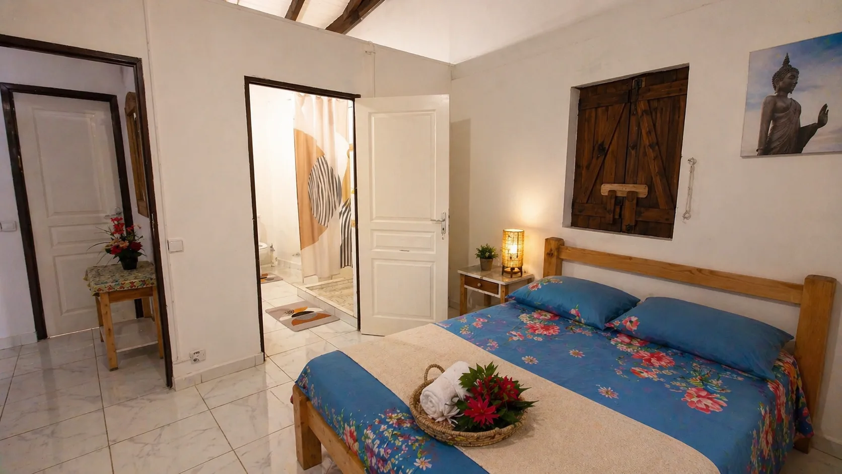 Deuxième chambre avec lit double, salle d'eau attenante et décoration tropicale